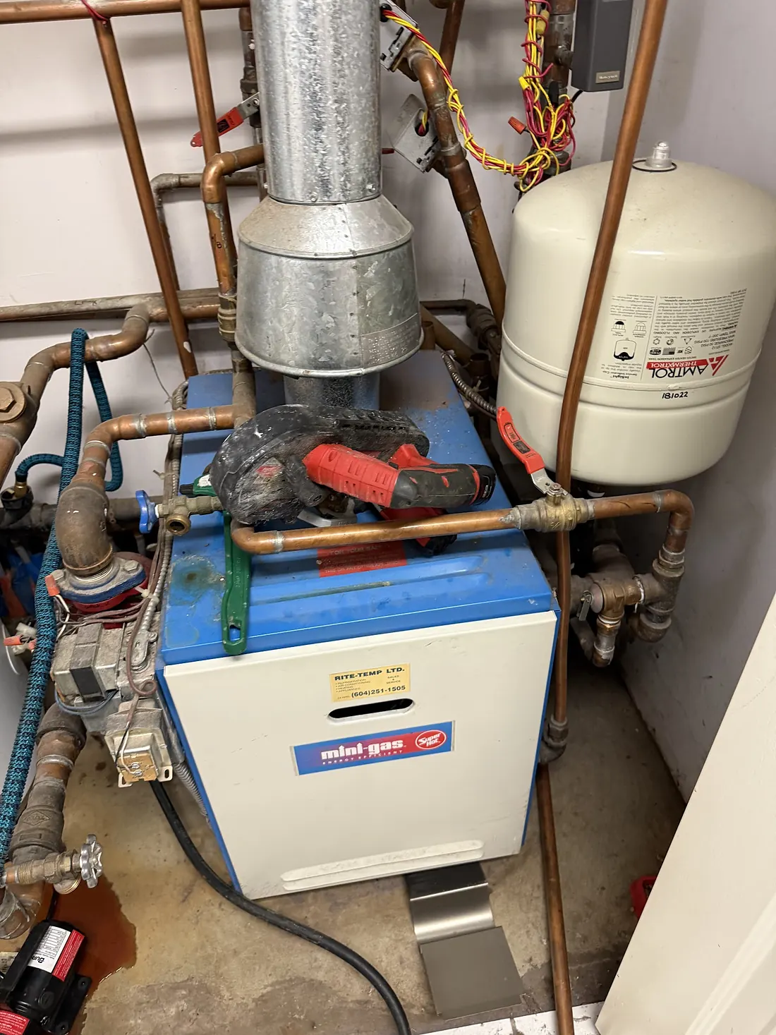 Gas-fired hydronic boiler with expansion tank and copper supply lines in a mechanical room