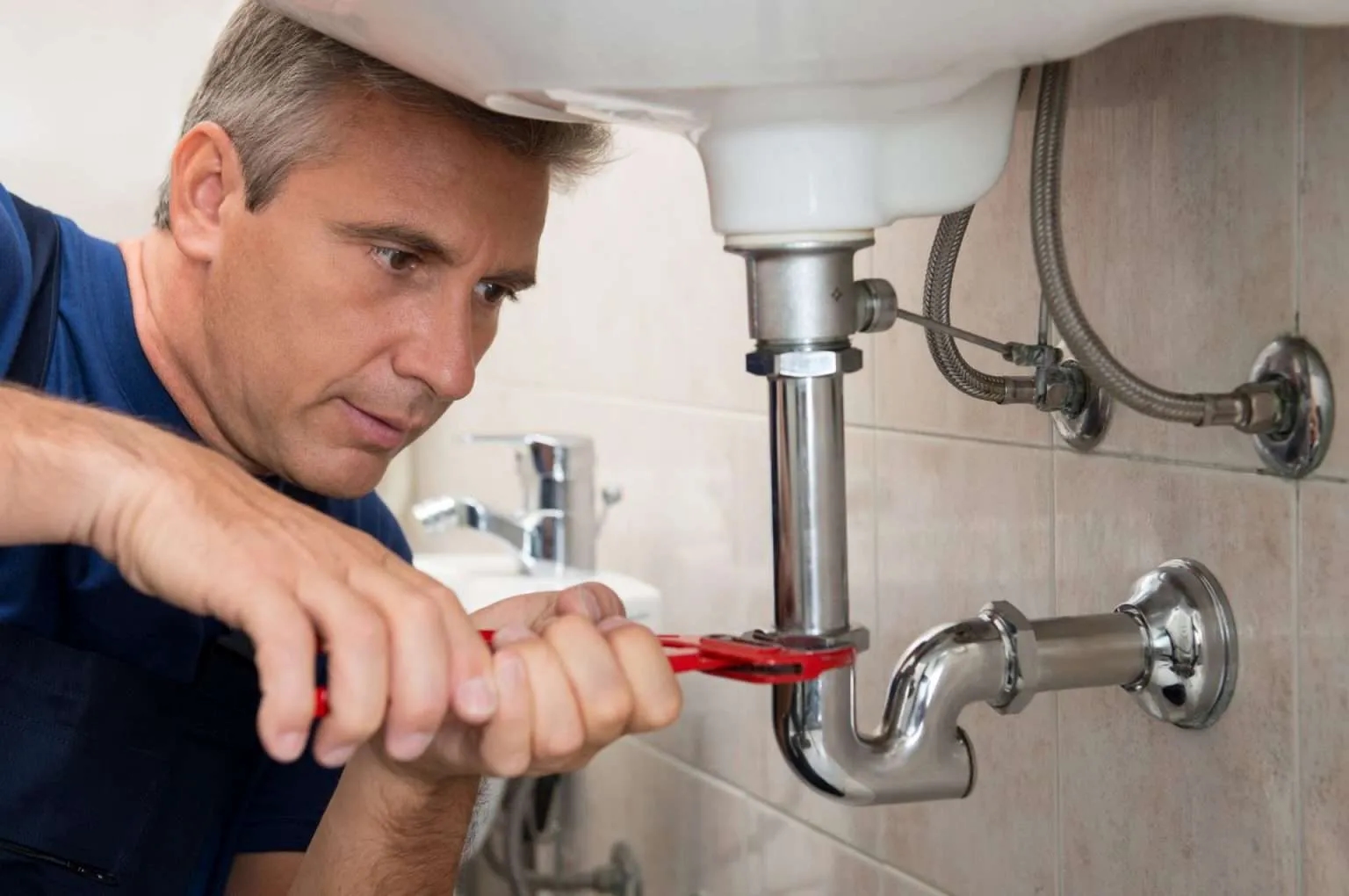 Plumber fixing a leak on a bathroom sink